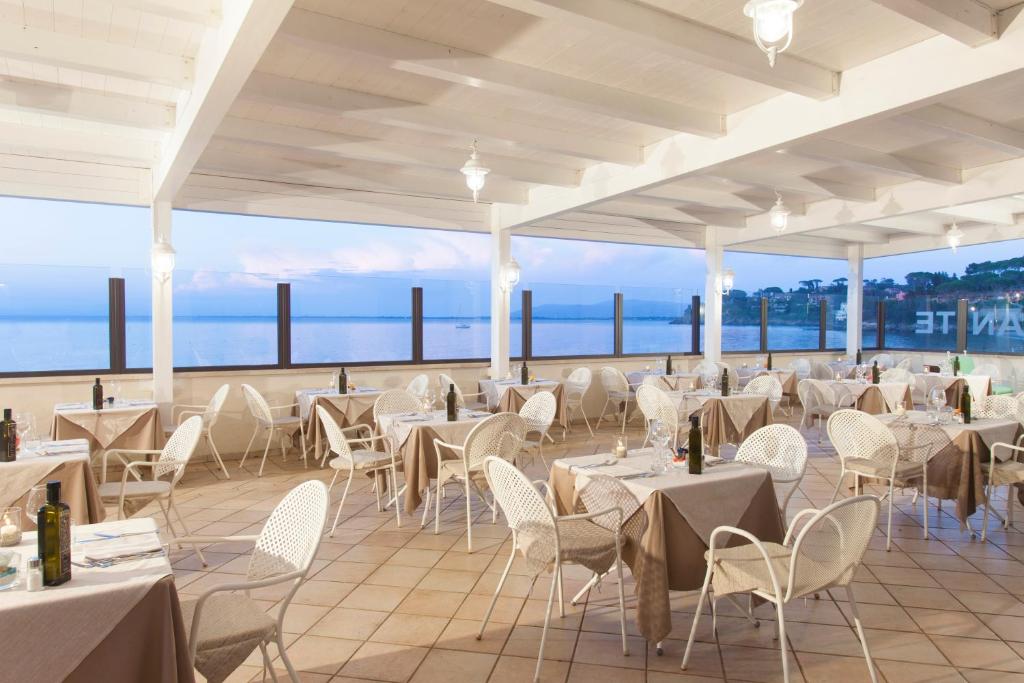 un restaurant avec des tables et des chaises et une vue sur l'océan dans l'établissement Baia D'Argento, à Porto Santo Stefano