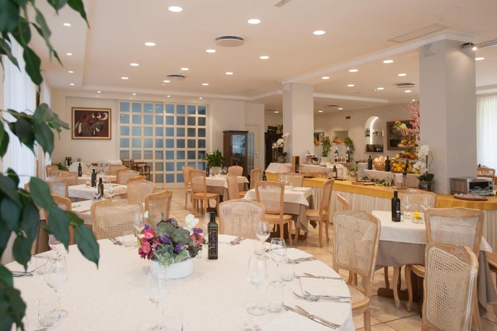 un restaurant avec des tables et des chaises avec des fleurs dessus dans l'établissement Baia D'Argento, à Porto Santo Stefano
