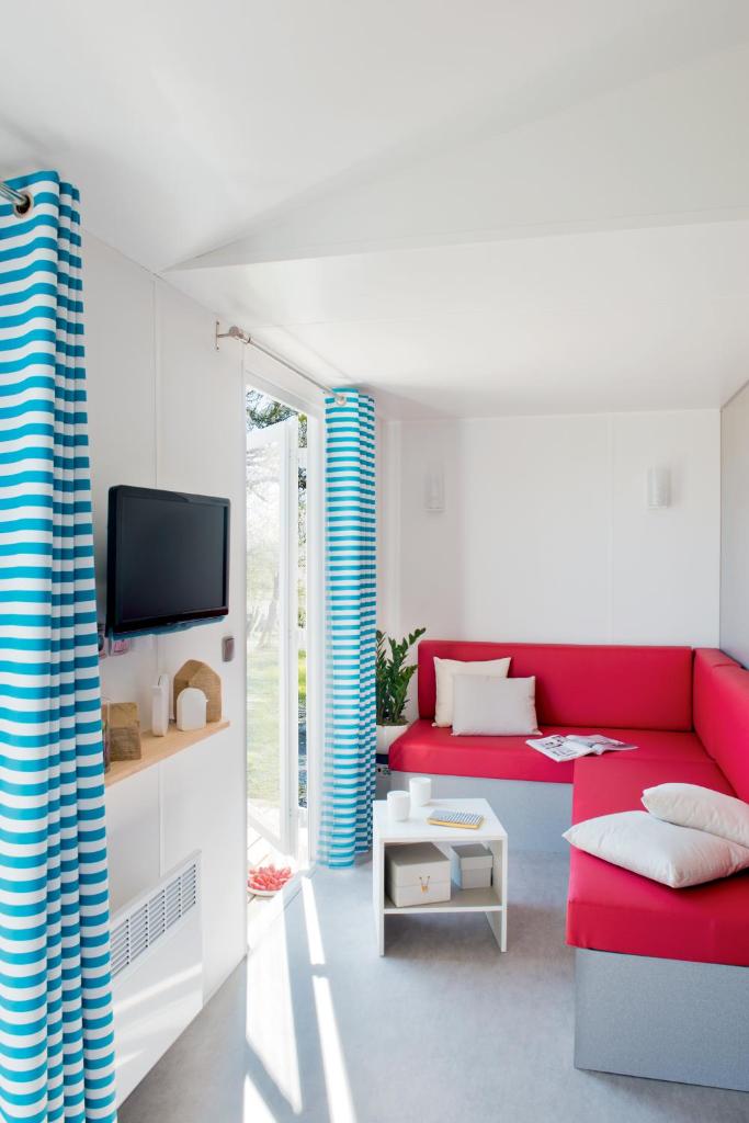 un salon avec un canapé rouge et une télévision dans l'établissement Camping Erreka, à Bidart