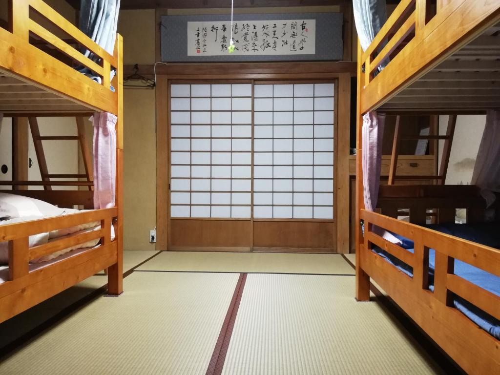 Cette chambre dispose d'une grande porte et de lits superposés. dans l'établissement Izu Hokkawa Seaside Guesthouse 伊豆北川の家, à Higashiizu