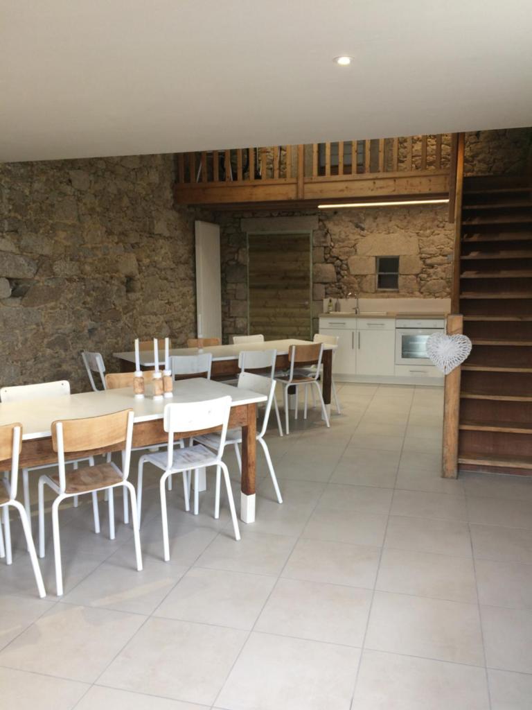 une salle à manger avec tables et chaises et une cuisine dans l'établissement LE PETIT MONTY Gite Côté Jardin, à Saint-Malo-du-Bois