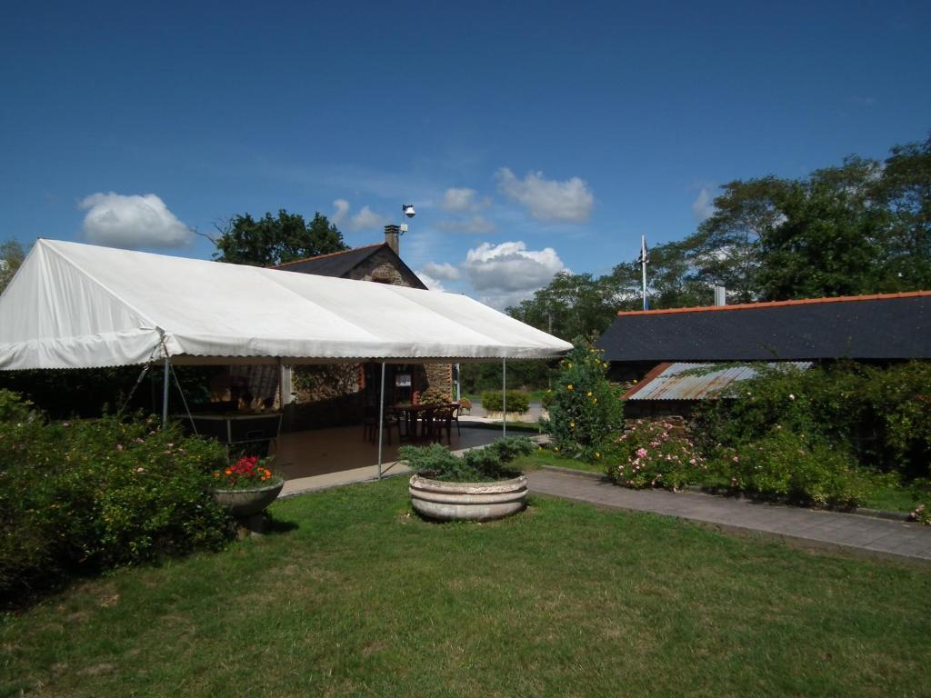 une tente blanche dans une cour à côté d'un bâtiment dans l'établissement Camping La Pindière, à Héric
