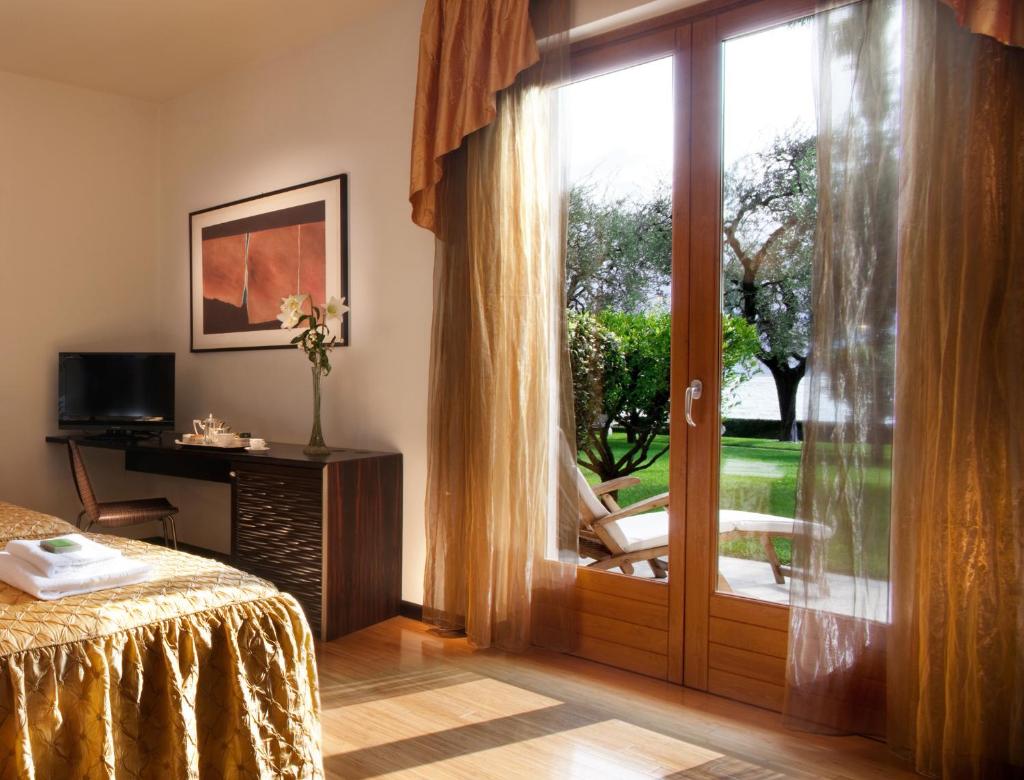 une chambre avec une porte coulissante en verre donnant sur un patio dans l'établissement Hotel Villa Giulia, à Gargnano
