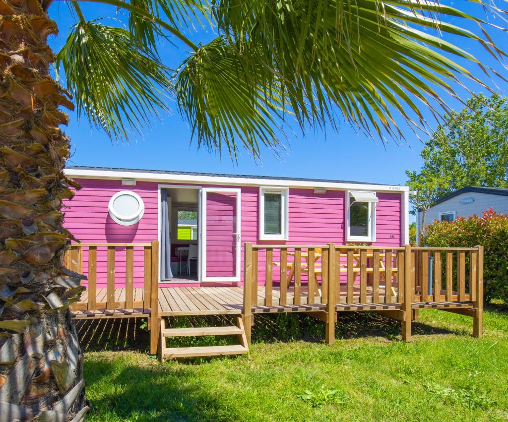 une petite maison rose avec une terrasse en bois dans l'établissement Camping Taxo Les Pins, à Argelès-sur-Mer