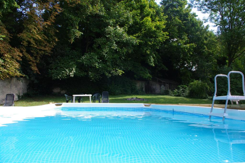 une piscine avec deux chaises et une table dans l'établissement Gite Allier, à Montaigu-le-Blin