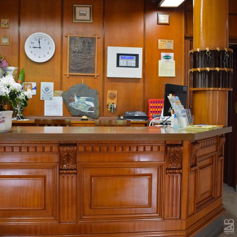 un comptoir en bois avec une horloge sur un mur dans l'établissement Hotel Gattuccio, à Cesenatico 79 autres photos