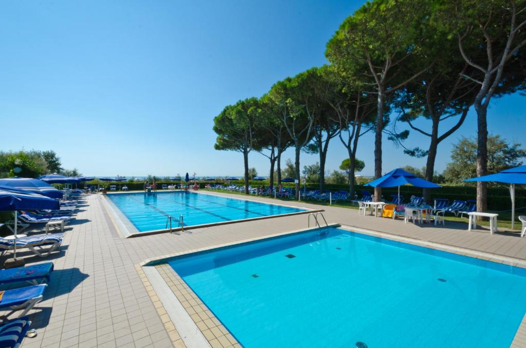 une piscine avec chaises longues et parasols dans un complexe hôtelier dans l'établissement Hotel King, à Lido di Jesolo