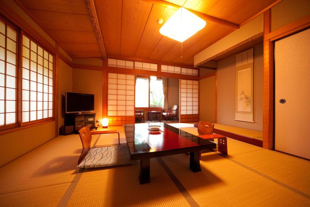 un salon avec une table et des chaises dans une pièce dans l'établissement Ryotei Tanokura, à Yufu