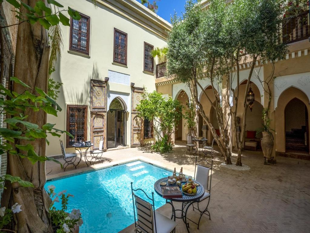 - une cour avec une piscine, une table et des chaises dans l'établissement Riad Il Parco dei Principi, à Marrakech