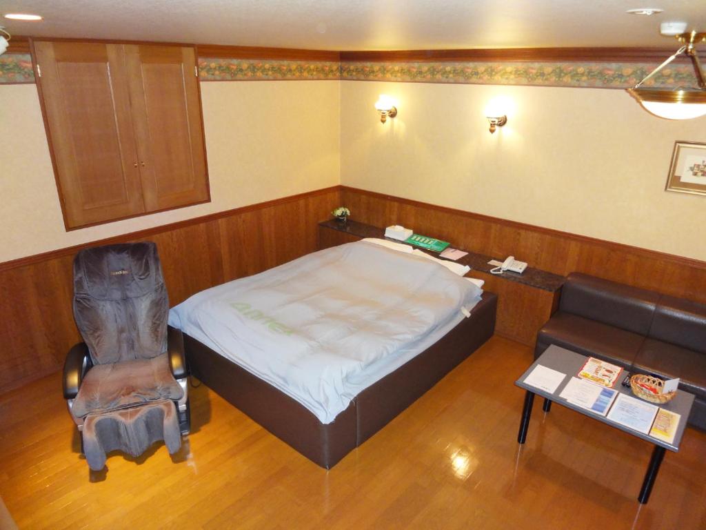 une chambre avec un lit, une chaise et une table dans l'établissement アネックスたまゆ 大人専用, à Matsue