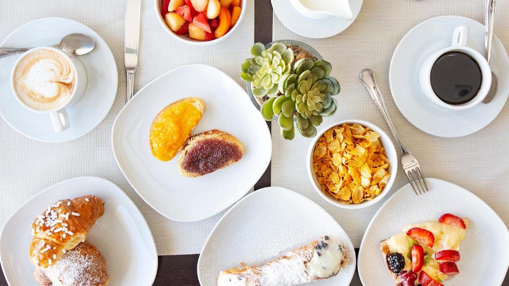 une table avec des plaques blanches de nourriture dans l'établissement Hotel Piccolo Mondo, à San Vito Lo Capo