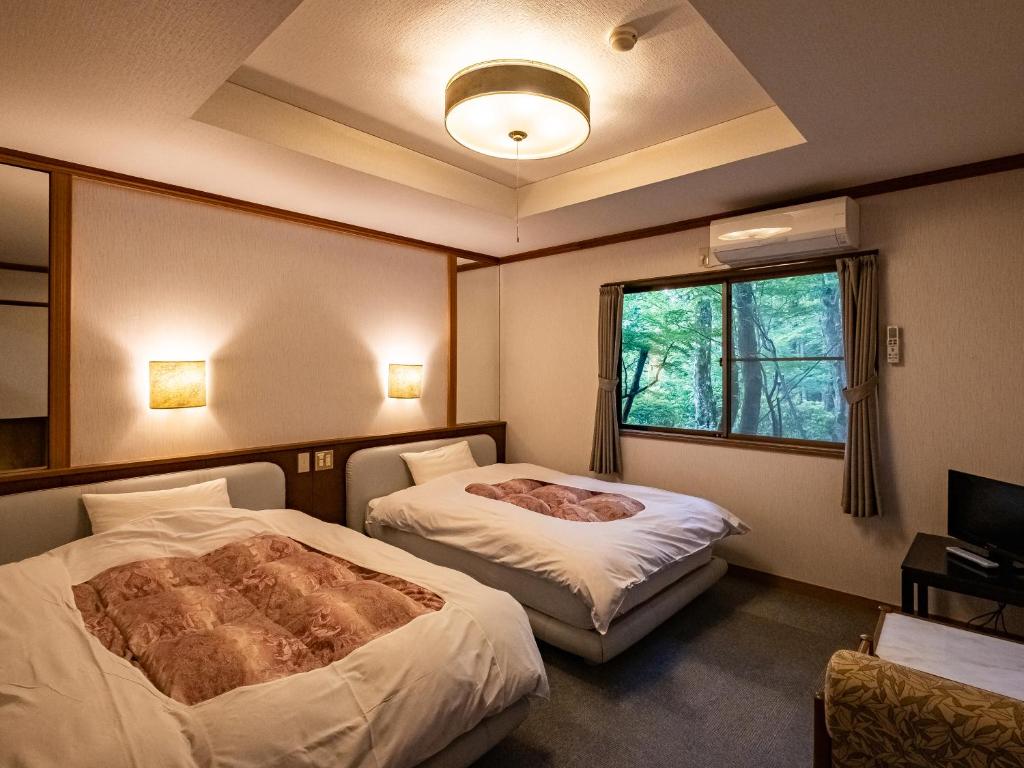 une chambre d'hôtel avec deux lits et une fenêtre dans l'établissement Hakone Onsen Sanso Nakamura, à Hakone