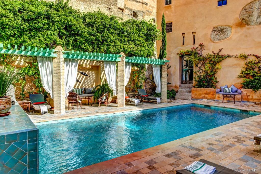 une piscine avec mobilier de jardin et une maison dans l'établissement Riad Laaroussa, à Fès