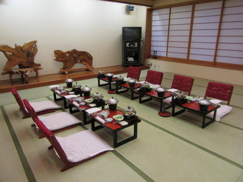 un groupe de tables et de chaises dans une pièce dans l'établissement Koganezaki Furofushi Onsen, à Fukaura