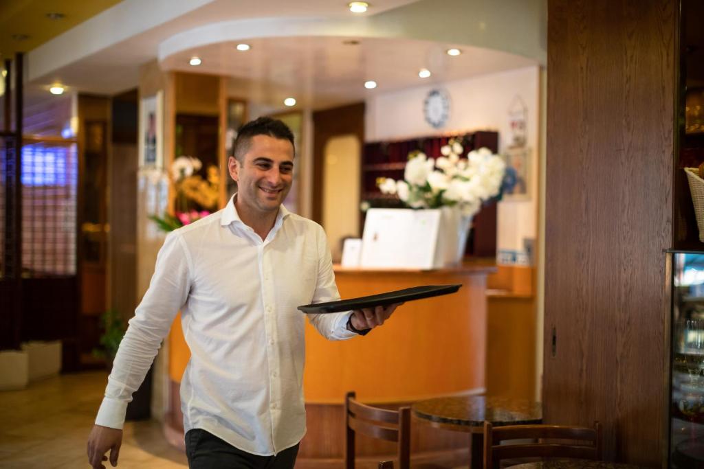 un homme en chemise blanche tenant une tablette dans l'établissement Hotel Kennedy, à Lido di Jesolo 58 autres photos