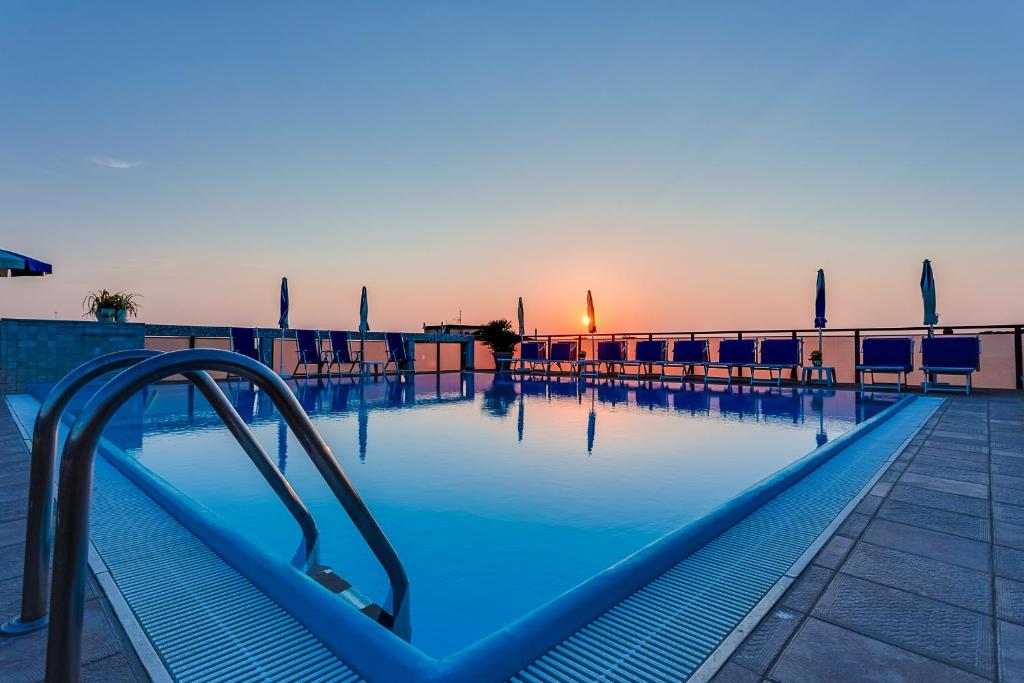 une piscine à l'eau bleue et un complexe hôtelier dans l'établissement Renzo Hotel, à Cesenatico