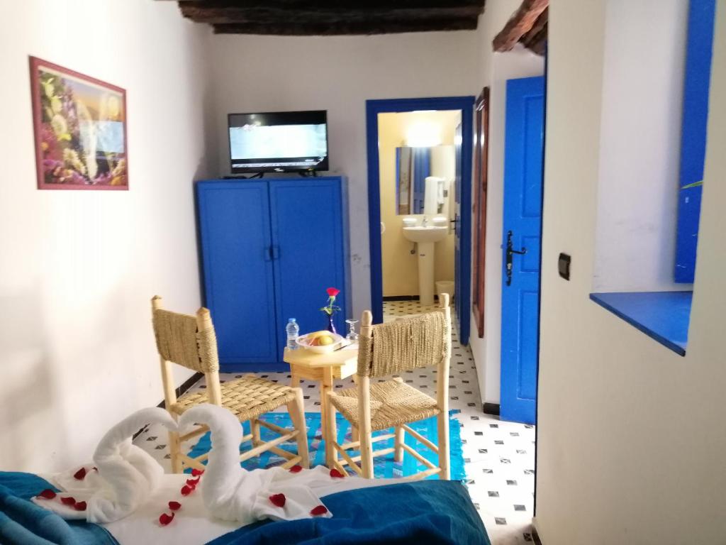 - un salon avec deux cygnes sur le lit et une table dans l'établissement Riad Zawia, à Essaouira