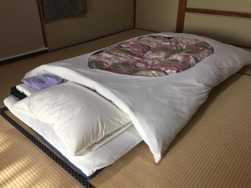 - un lit blanc avec un oreiller au sol dans l'établissement Hinodeya, à Itō