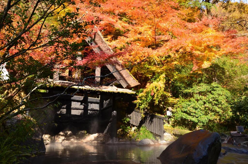 un pont sur une rivière avec des arbres colorés dans l'établissement Kurokawa Onsen Oku no Yu, à Minamioguni