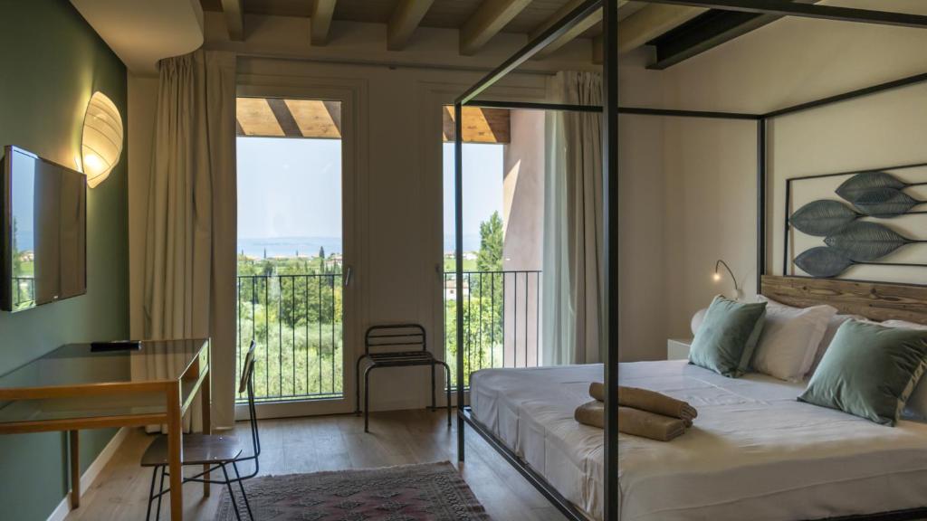 - une chambre avec un lit, un bureau et un balcon dans l'établissement Villa Collivo, à Lazise