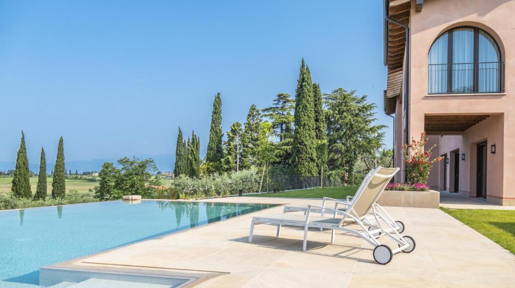 une chaise blanche assise à côté d'une piscine dans l'établissement Villa Collivo, à Lazise