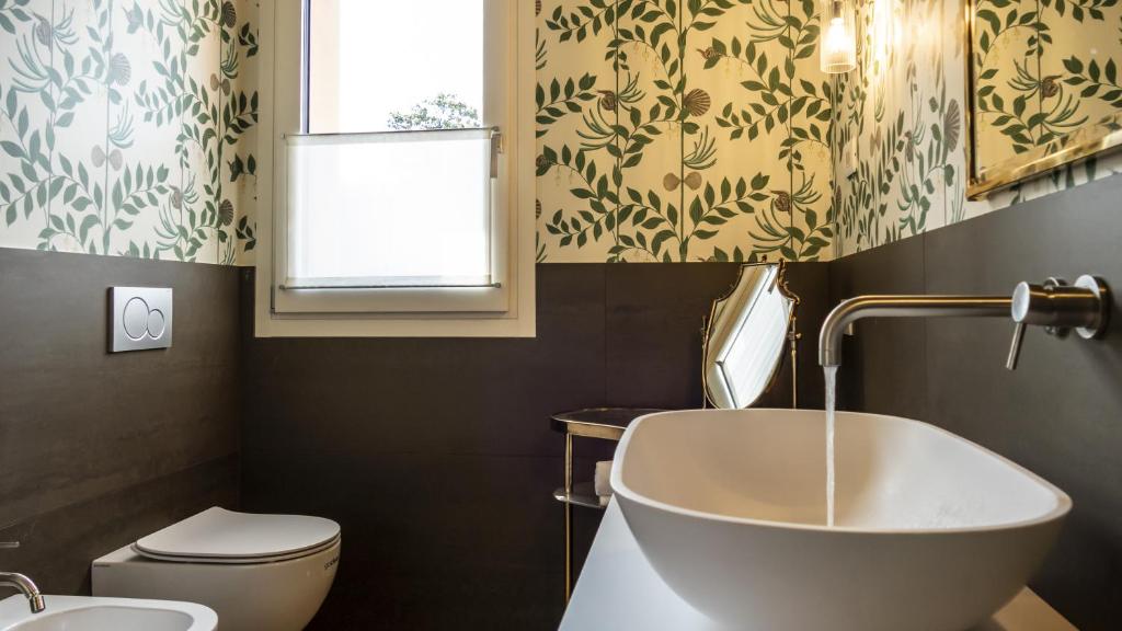 une salle de bain avec un lavabo et des toilettes et une fenêtre dans l'établissement Villa Collivo, à Lazise 23 autres photos