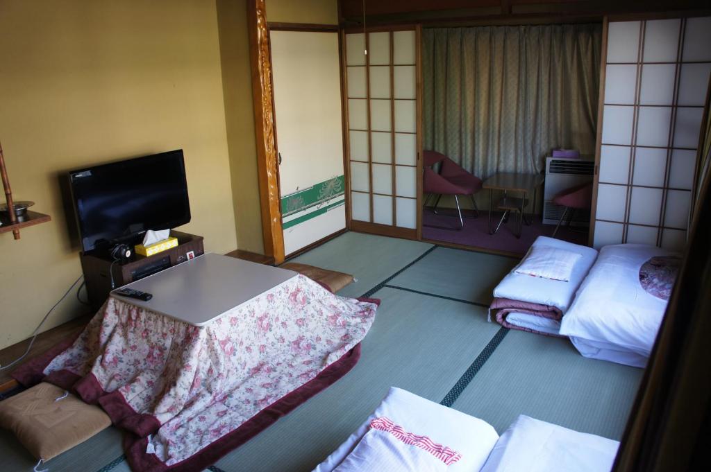 une chambre d'hôtel avec un lit et une télévision dans l'établissement Miyoshiya Ryokan, à Tanabe