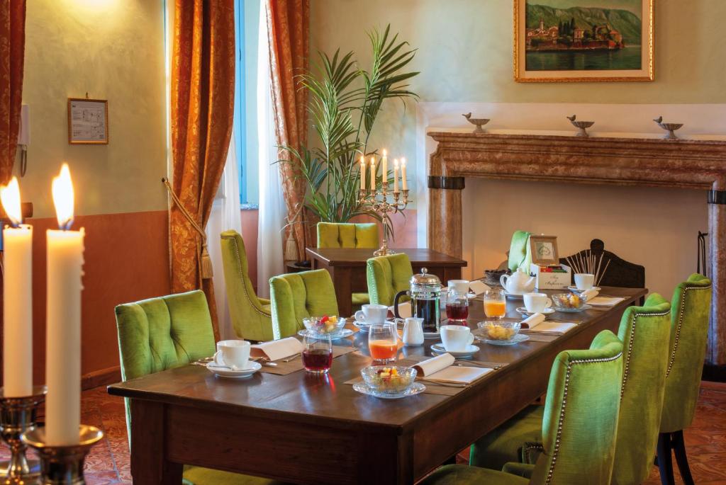 une salle à manger avec une grande table et des chaises vertes dans l'établissement Palazzo Del Vicerè, à Lezzeno