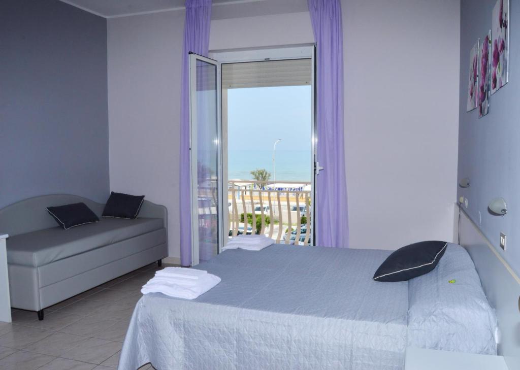 une chambre avec un lit, un canapé et une fenêtre dans l'établissement Hotel Perla, à Senigallia