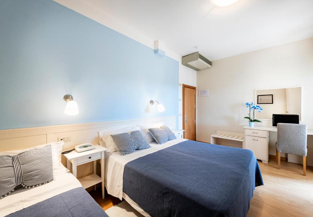 une chambre d'hôtel avec deux lits et un bureau dans l'établissement Hotel Andreaneri, à Marina di Pietrasanta