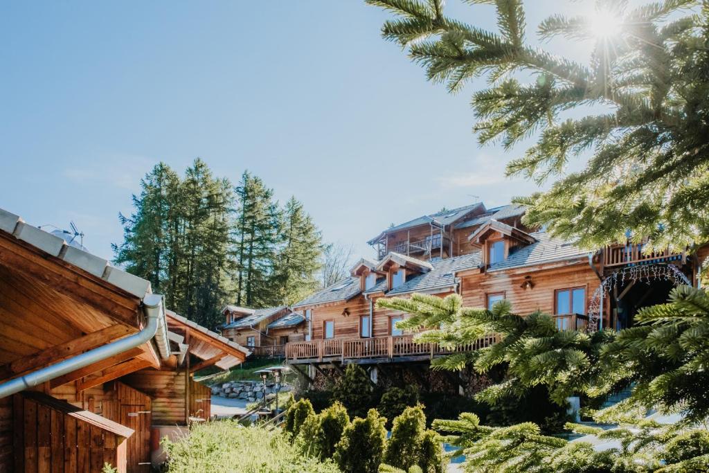 une cabane en rondins avec des arbres au premier plan dans l'établissement Résidence Sunêlia Les Logis d'Orres, aux Orres