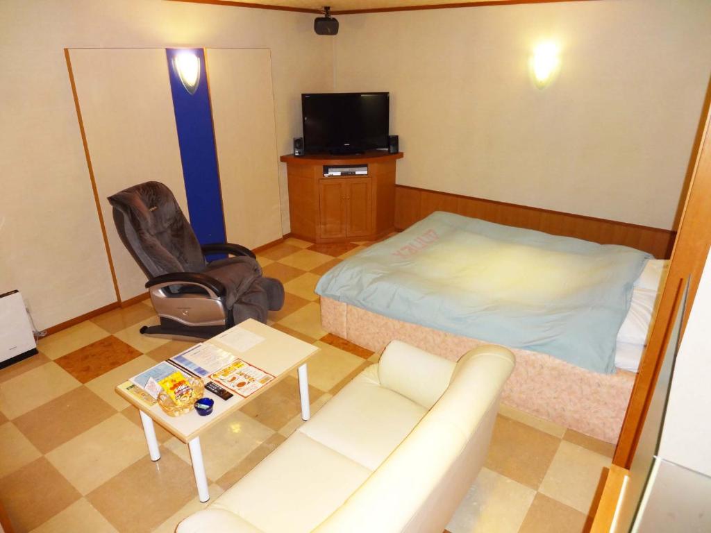 Cette chambre comprend un lit, un canapé et une table. dans l'établissement アネックスたまゆ 大人専用, à Matsue