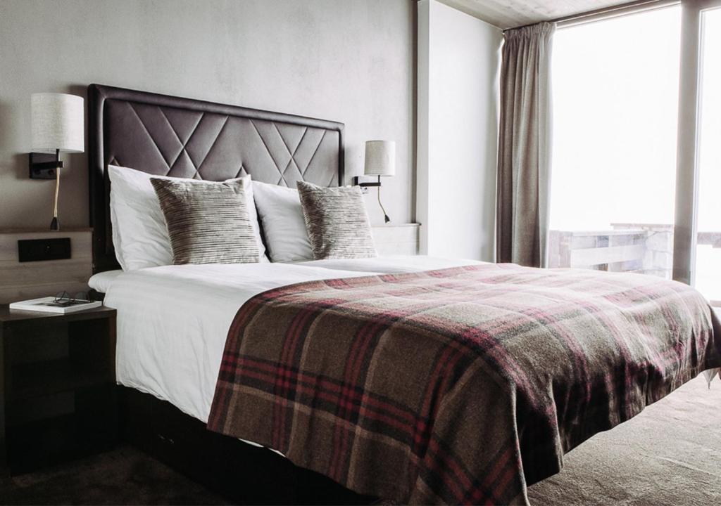 - une chambre avec un grand lit et une couverture dans l'établissement Langley Hôtel Tignes 2100, à Tignes