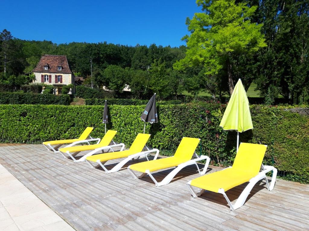 - une rangée de chaises et de parasols jaunes sur une terrasse dans l'établissement Camping Le Céou, à Saint-Cybranet