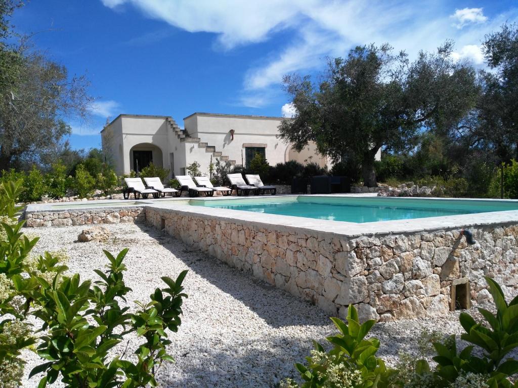 une piscine avec un mur en pierre à côté d'une maison dans l'établissement Gli Ulivi, à Giurdignano