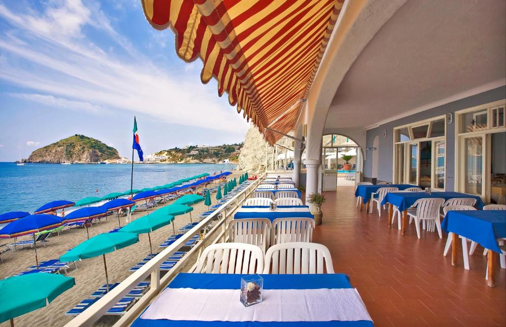 une rangée de chaises et de parasols sur une plage dans l'établissement Hotel Vittorio Beach Resort, à Ischia