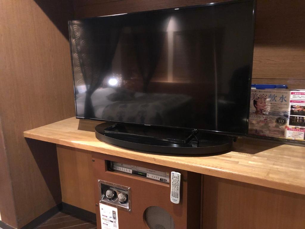 une grande télévision noire assise au-dessus d'une table dans l'établissement Restay Mito (Adult Only), à Mito