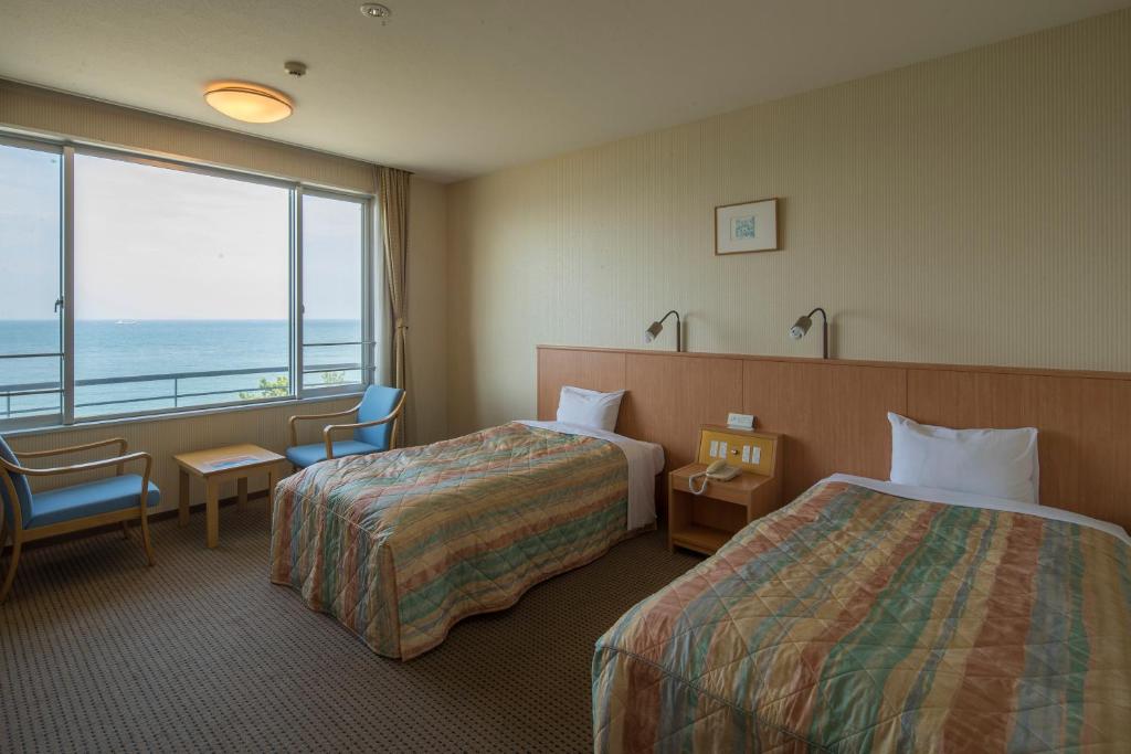 une chambre d'hôtel avec deux lits et vue sur l'océan dans l'établissement Kyukamura Shikanoshima, à Fukuoka 37 autres photos