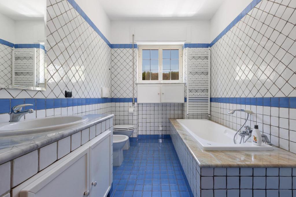 La salle de bains bleue et blanche est pourvue d'une baignoire et de toilettes. dans l'établissement Villa Emary by Perle di Puglia, à San Vito dei Normanni
