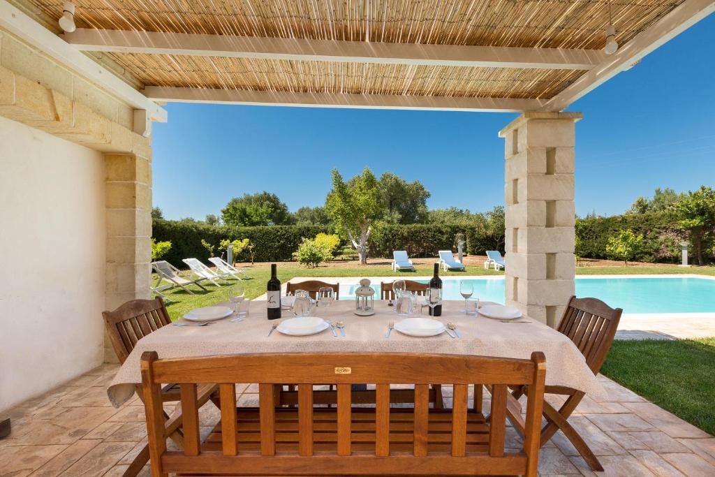 un patio avec une table et des chaises et une piscine dans l'établissement Villa Emary by Perle di Puglia, à San Vito dei Normanni