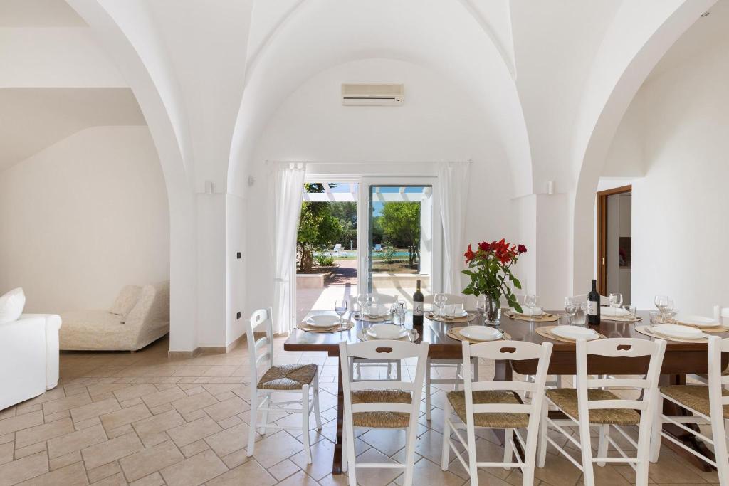une salle à manger blanche avec une table et des chaises dans l'établissement Villa Emary by Perle di Puglia, à San Vito dei Normanni