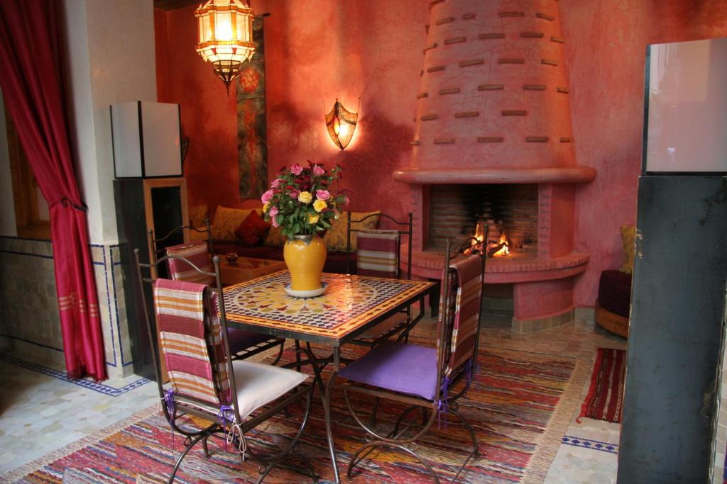 une salle à manger avec une table et une cheminée dans l'établissement Riad Kenzo, à Marrakech