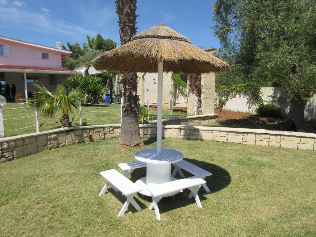 une table et deux chaises sous un parasol de paille dans l'établissement Tenuta Placella, à Serranova