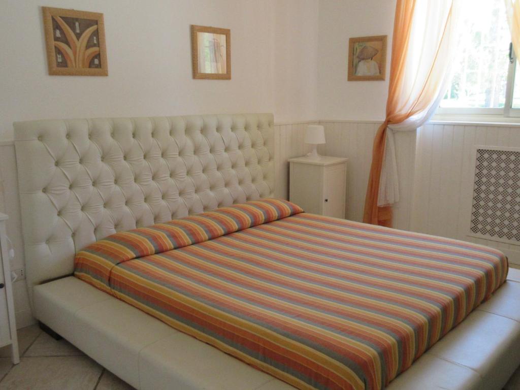 - un grand lit blanc avec une couverture rayée dans l'établissement Tenuta Placella, à Serranova