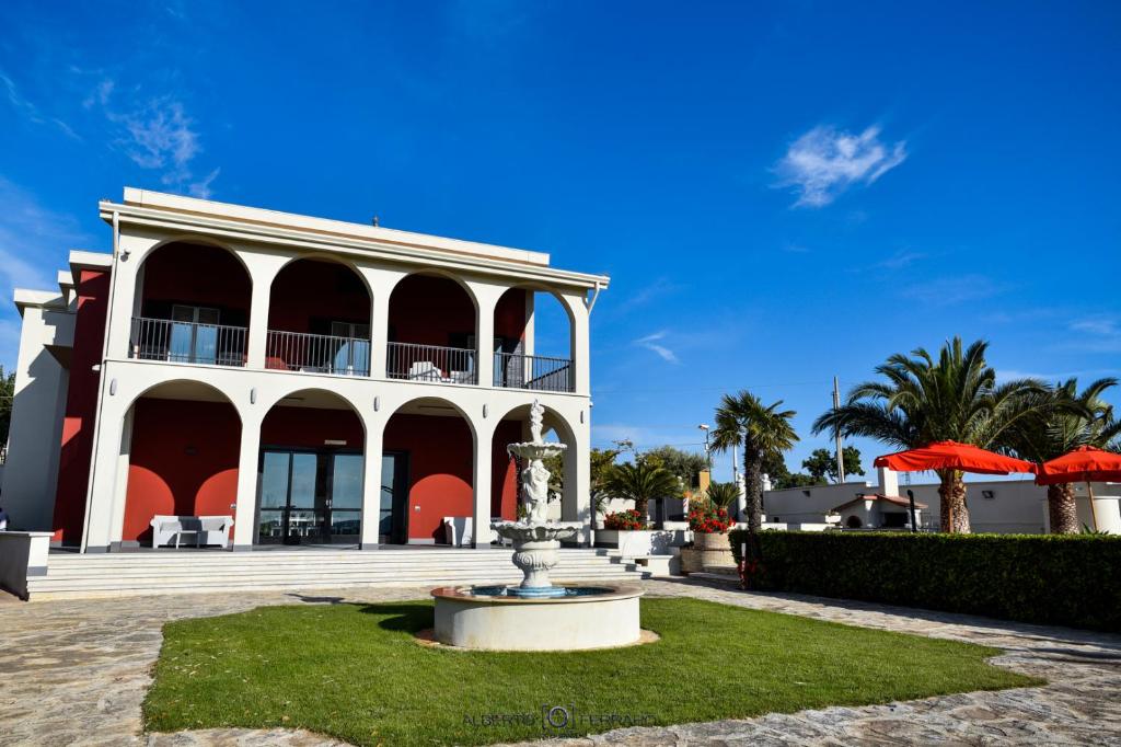 un grand bâtiment blanc avec une fontaine devant lui dans l'établissement Villa Elena, à Camastra ex Solfara