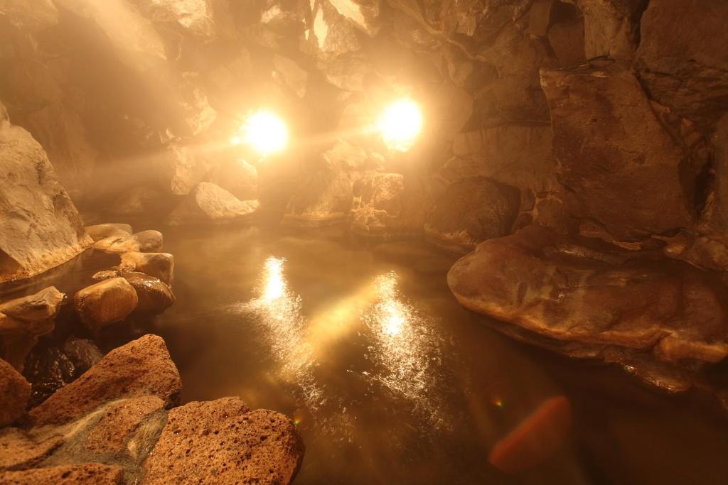 Une grotte avec des rochers et des lumières dans l'eau dans l'établissement Shimizu Ryokan, à Yufu
