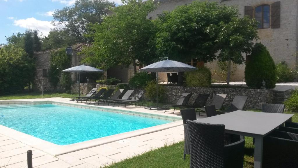 - une piscine avec des chaises, une table et un parasol dans l'établissement Gites La Peyroulière, à Aurignac