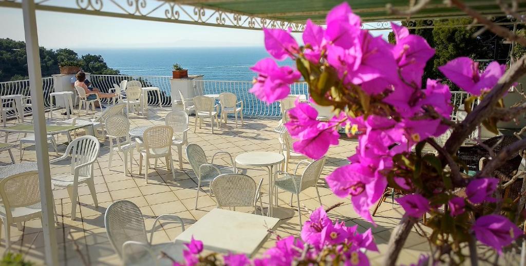 un patio avec des tables et des chaises et des fleurs violettes dans l'établissement Hotel Desiree, à Sorrente 55 autres photos