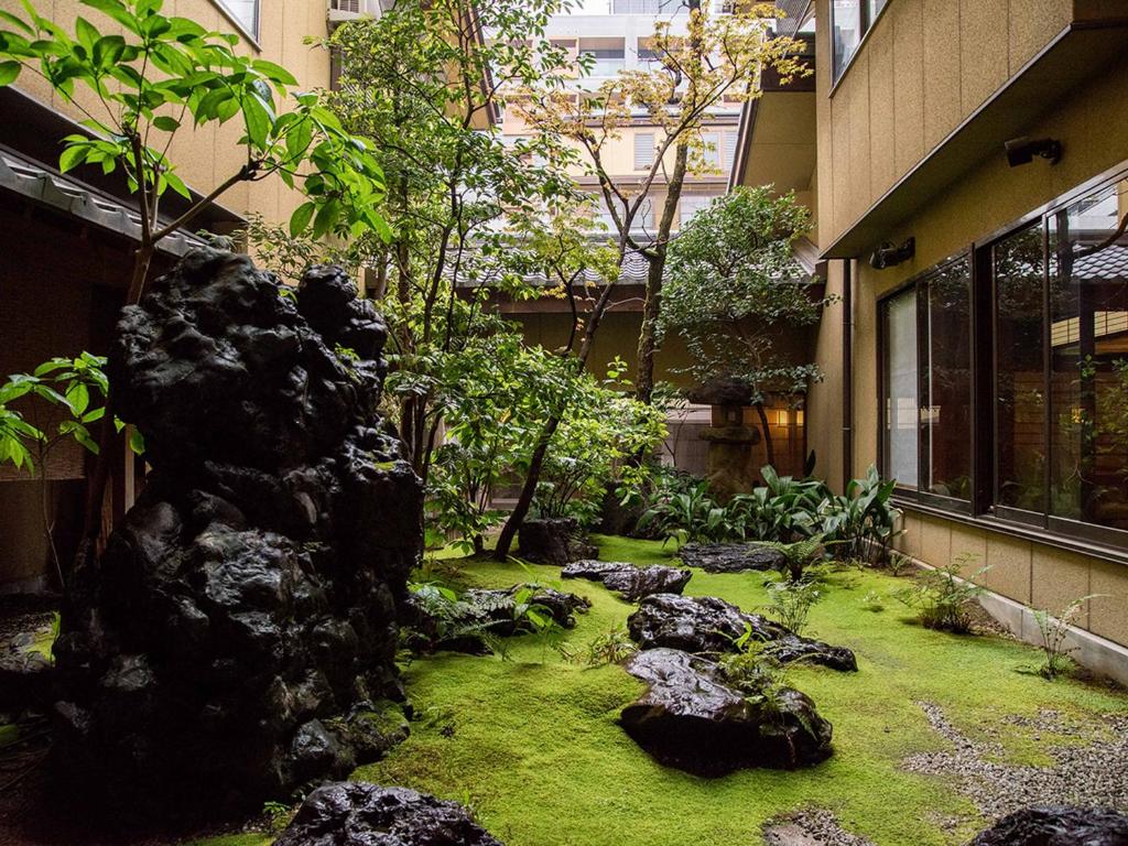 un jardin avec des rochers et de la pelouse devant un bâtiment dans l'établissement Yamatoya Besso, à Matsuyama