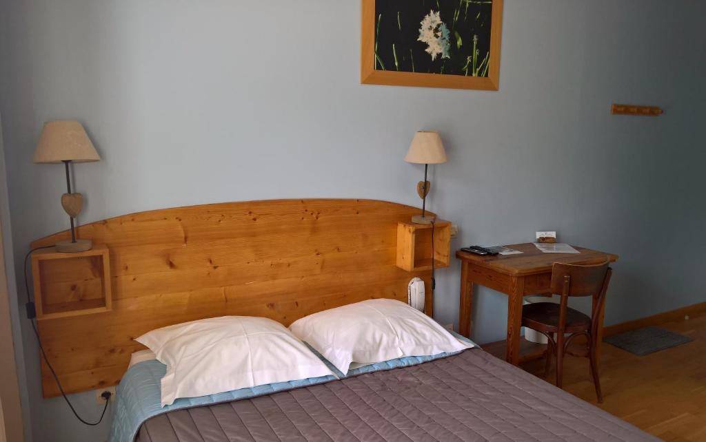 - une chambre avec un lit doté d'une tête de lit en bois et d'une table dans l'établissement Les Fauvettes, à Saint-Léger-les-Mélèzes